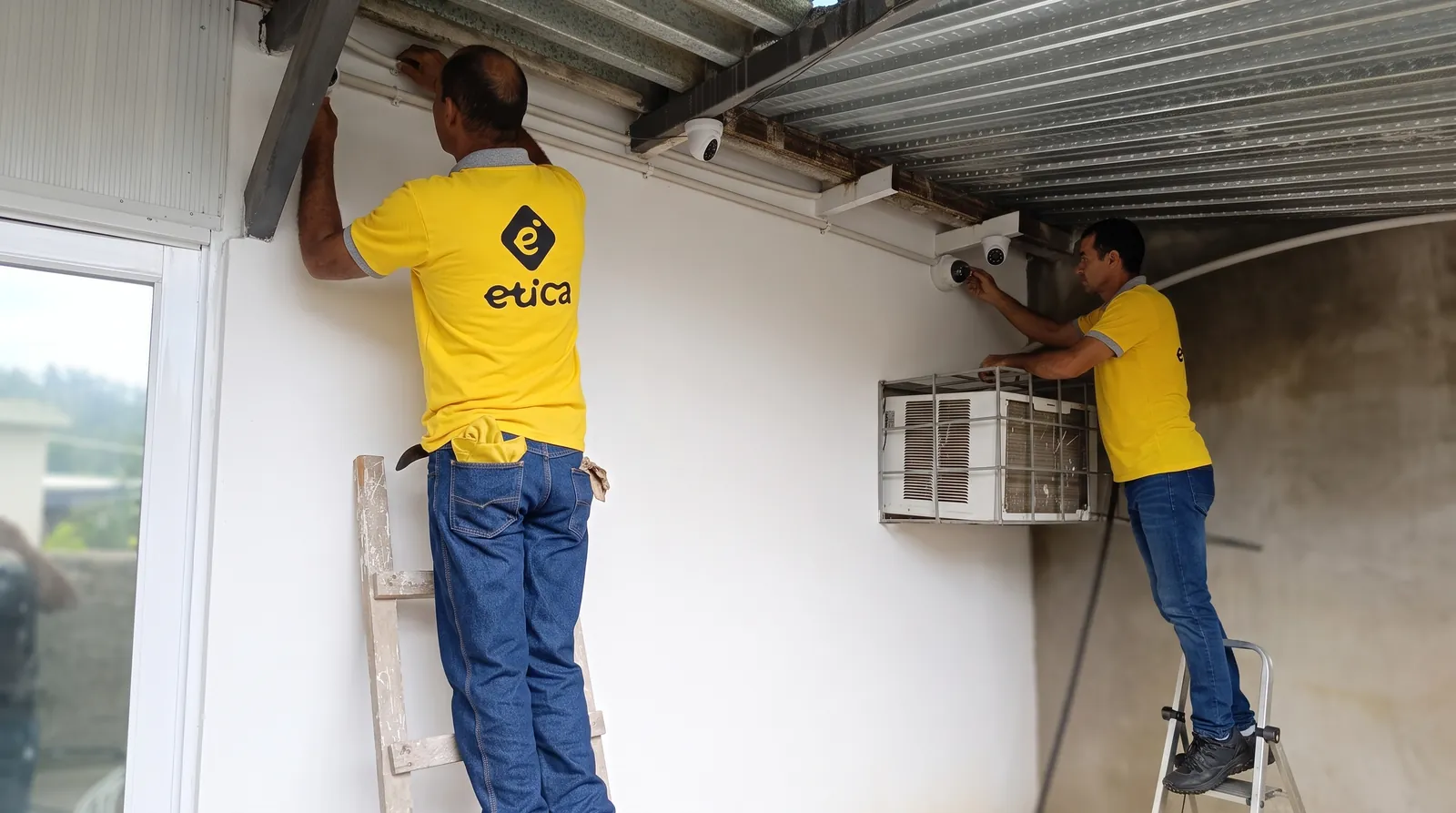 Técnicos de E.T.I., C.A. instalando cámaras de seguridad bajo un techo